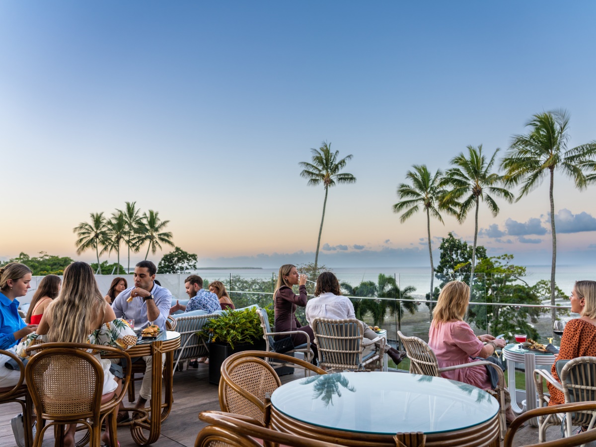 People are sitting at an outdoor restaurant along the esplanade enjoying their meals